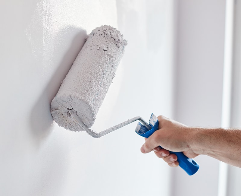 A painter uses a paint roller to apply a new interior paint colour