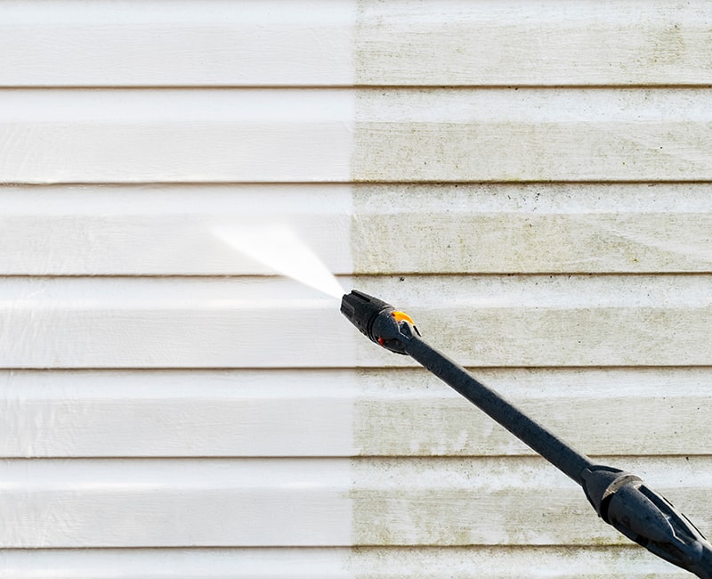 A pressure washer blasts away dirt and debris to refresh the look of siding