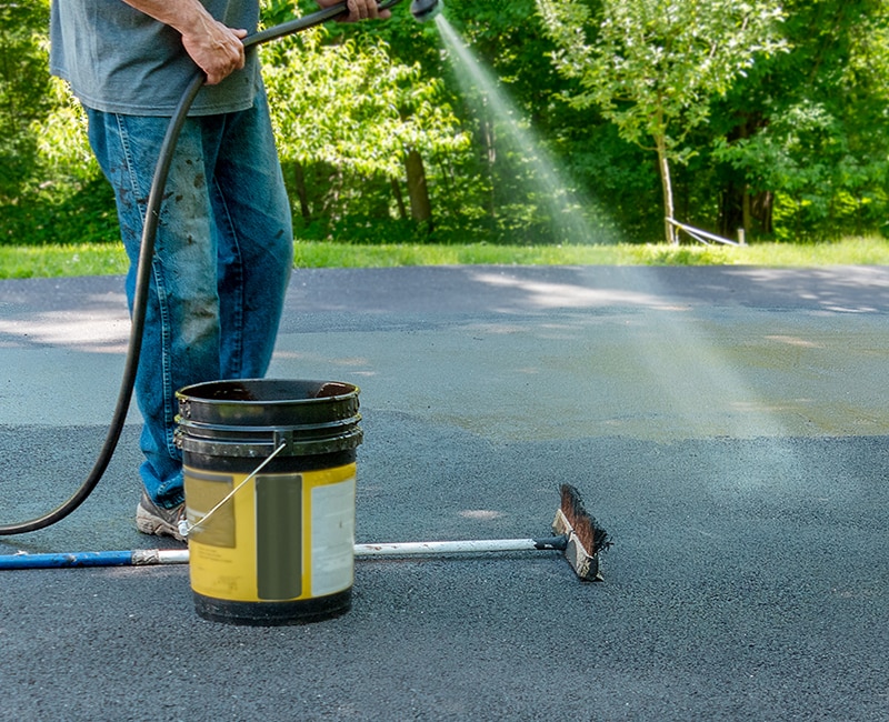 A pavement resealer sprays the surface of an asphalt driveway to protect it from wear and tear