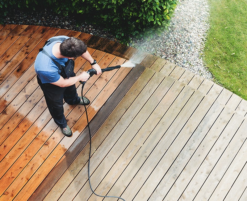 An outdoor surface is prepared for painting or staining with a heavy cleaning using a pressure washer